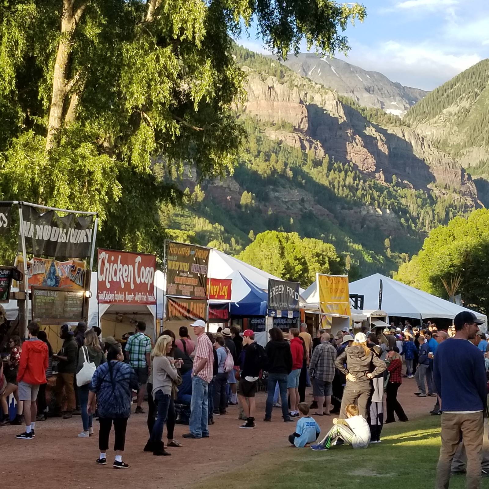 Festival food vendors in Telluride Town Park beneath the mountains