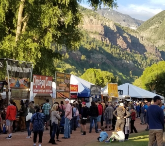 Festival food vendors in Telluride Town Park beneath the mountains