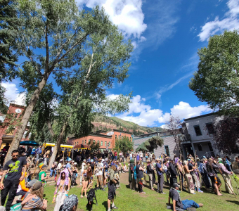 Wide view of Camp Alderwild festivalgoers in Elks Park beneath the mountains of Telluride