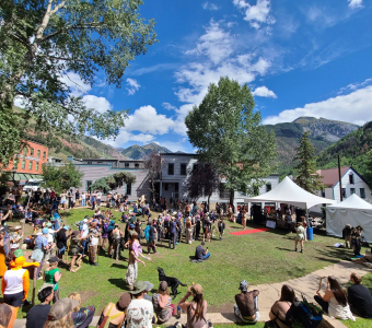 Camp Alderwild stick tournament filling Elks Park in downtown Telluride with mountains beyond