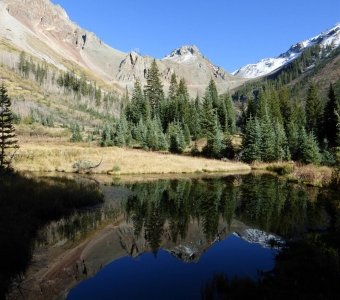 Mountain pond reflecting the slopes below Ophir Pass near Ophir, Colorado