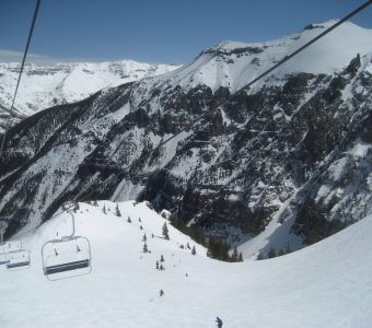 Skier in Revelation Bowl beneath the high alpine cliffs at Telluride Ski Resort.