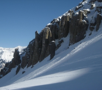 Steep snow-covered terrain and volcanic rock towers at Telluride Ski Resort.