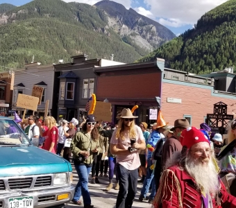 Telluride Mushroom Festival parade with mushroom-costumed marchers beneath the San Juan Mountains