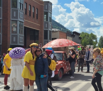 Mushroom Festival parade participants with colorful mushroom costumes and a mushroom-topped car in downtown Telluride