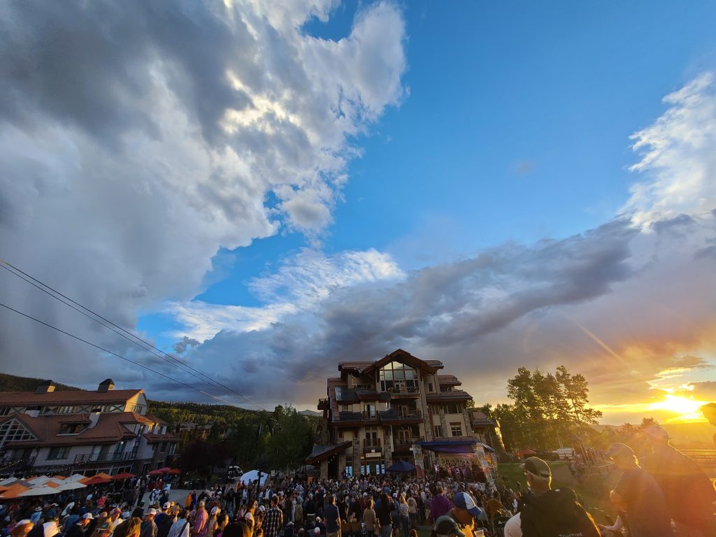 Easy Jim performing at the Mountain Village Sunset Concert Series beneath dramatic storm clouds and sunset