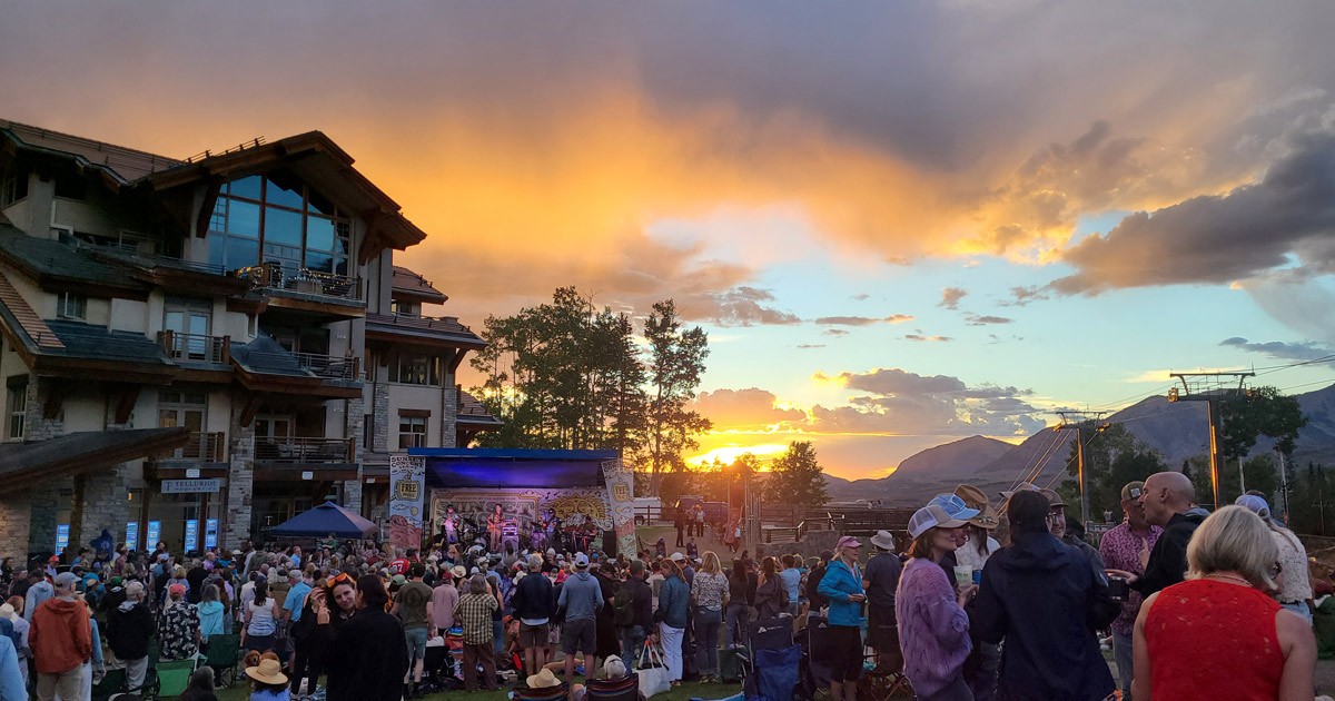 Easy Jim performing at the Mountain Village Sunset Concert Series as the sun sets over the crowd at Sunset Plaza